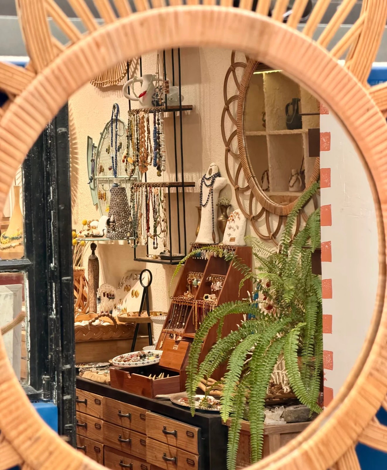 Finished handmade jewelry on display through a rattan mirror